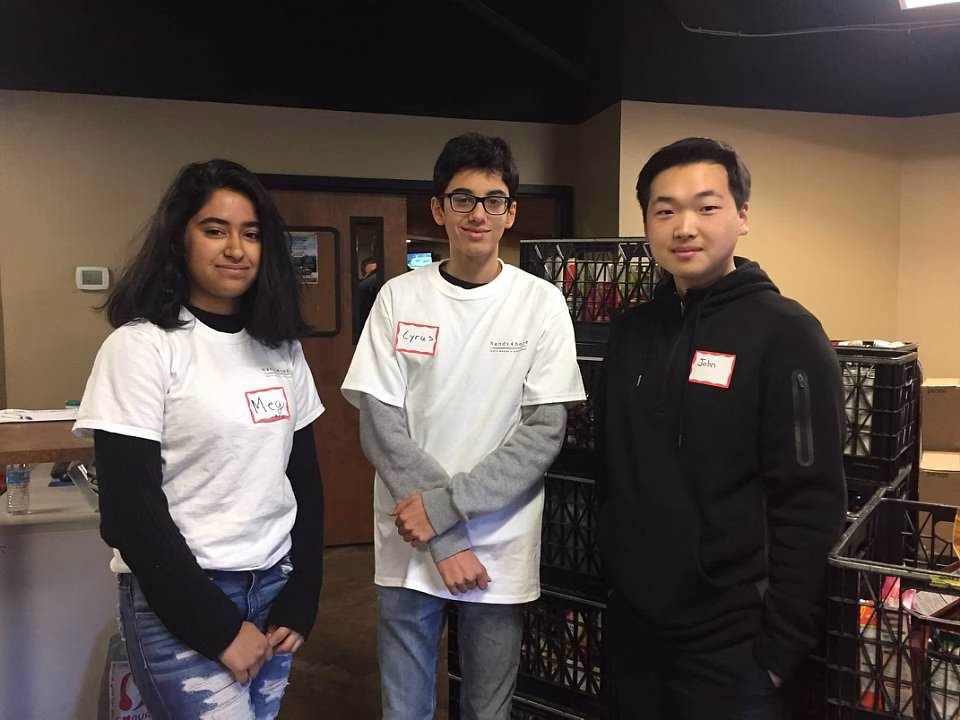 Three teenagers volunteering at a food bank, showcasing their dedication to helping others
