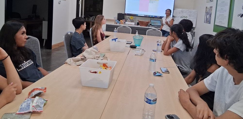 Students seated at a long table in a classroom setting