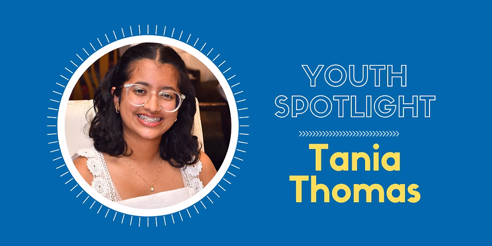 Tania Thomas is a young woman with a bright smile and glasses, posing for a photo.